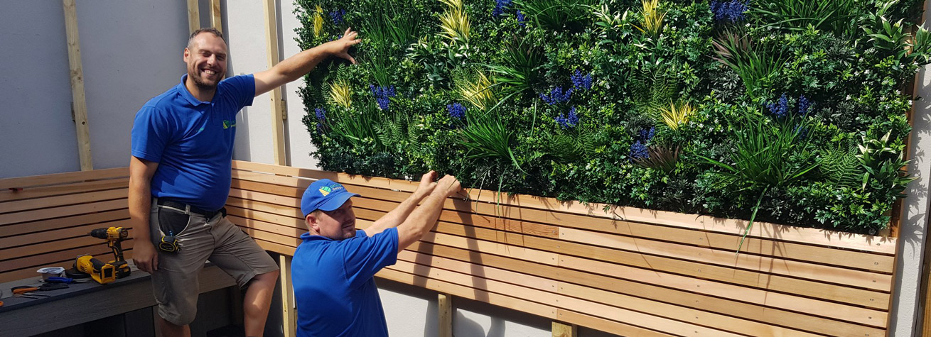 two landscapers installing artificial green wall panels